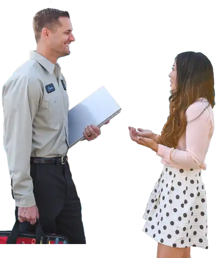 A man holding a toolbox and folder talks to a woman in a pink blouse and polka dot skirt against a white background.